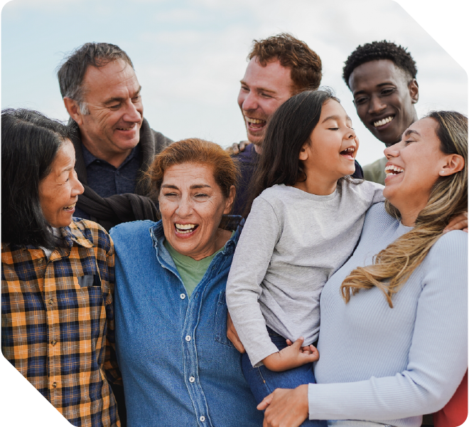A multi generational family smiling and laughing outside.